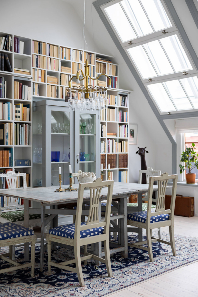 Яркий интерьер мансардной квартиры синим диваном и библиотекой
