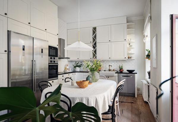Белый интерьер шведской квартиры с душевным декором и растениями