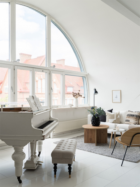 Белоснежная мансардная квартира с арочным окном и роялем