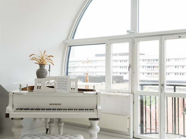Белоснежная мансардная квартира с арочным окном и роялем